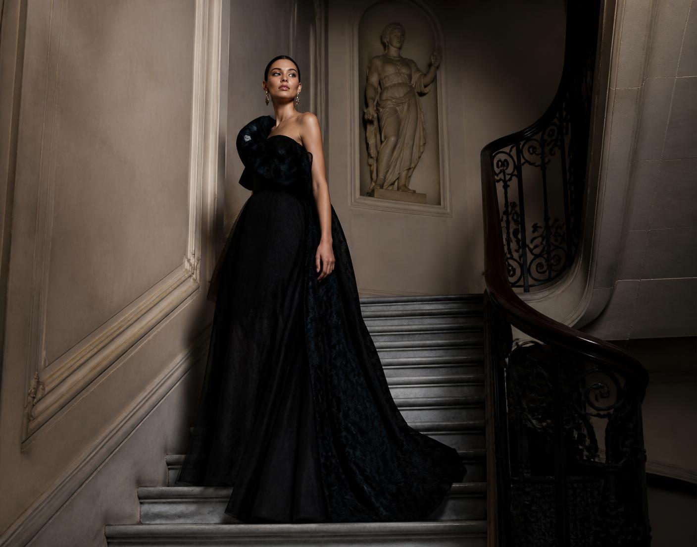 Model in a black LaDivine couture gown on a marble staircase